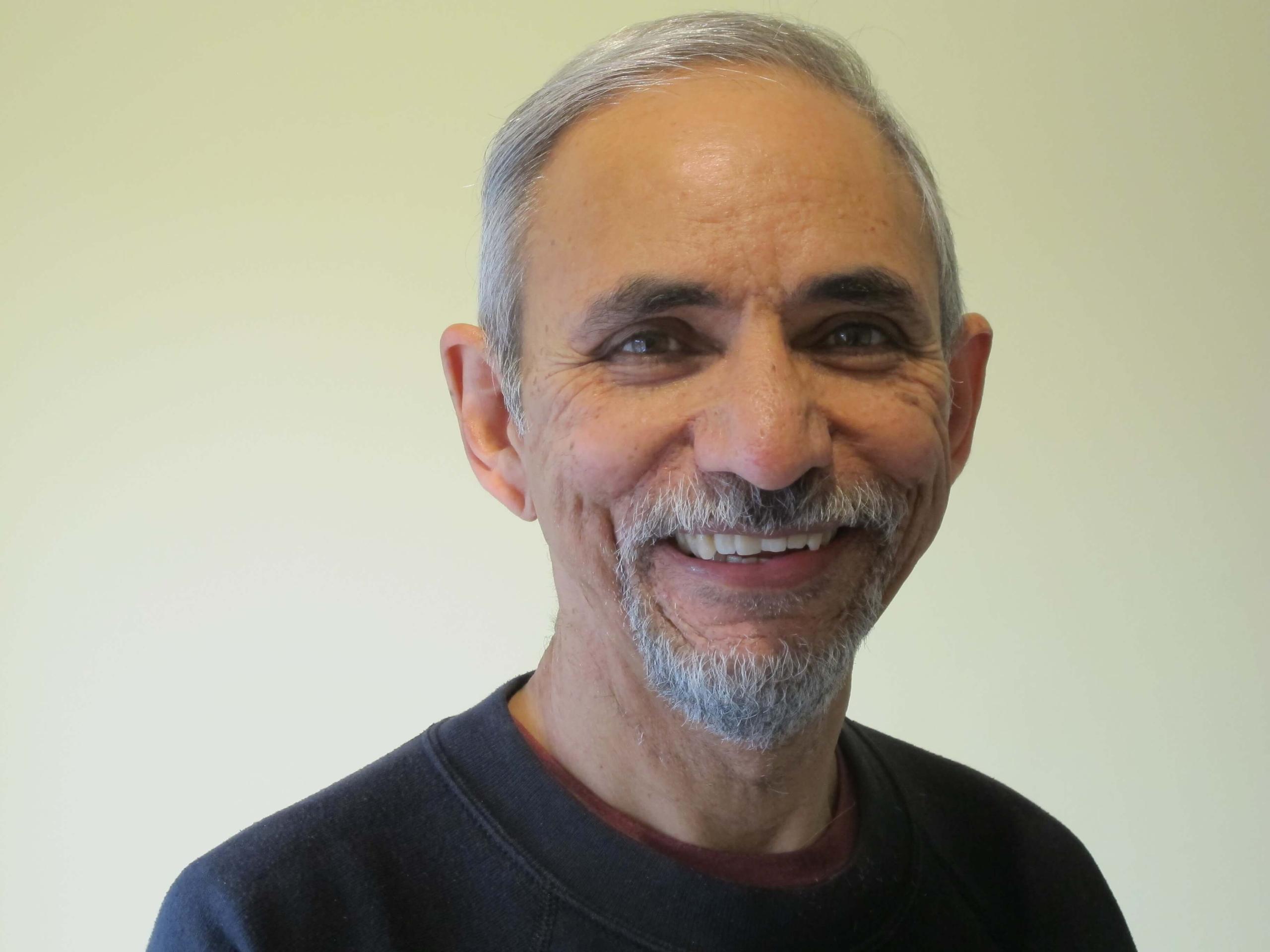 A picture of a south asian man smiling at the camera
