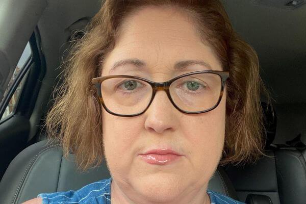 A picture of a woman in glasses sat in a car