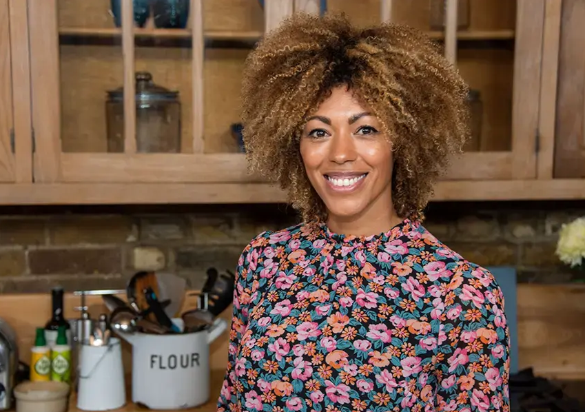 Dr Zoe Williams smiling to camera in her kitchen