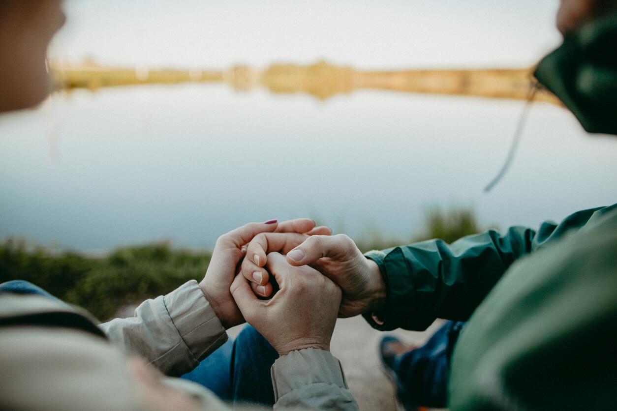 Close up of a couples' hands by a lake