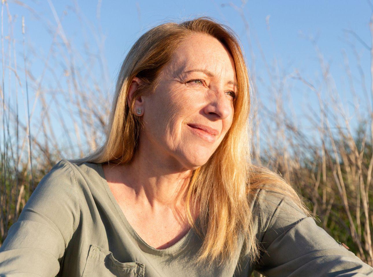 Middle aged woman sitting in the sunshine in a field