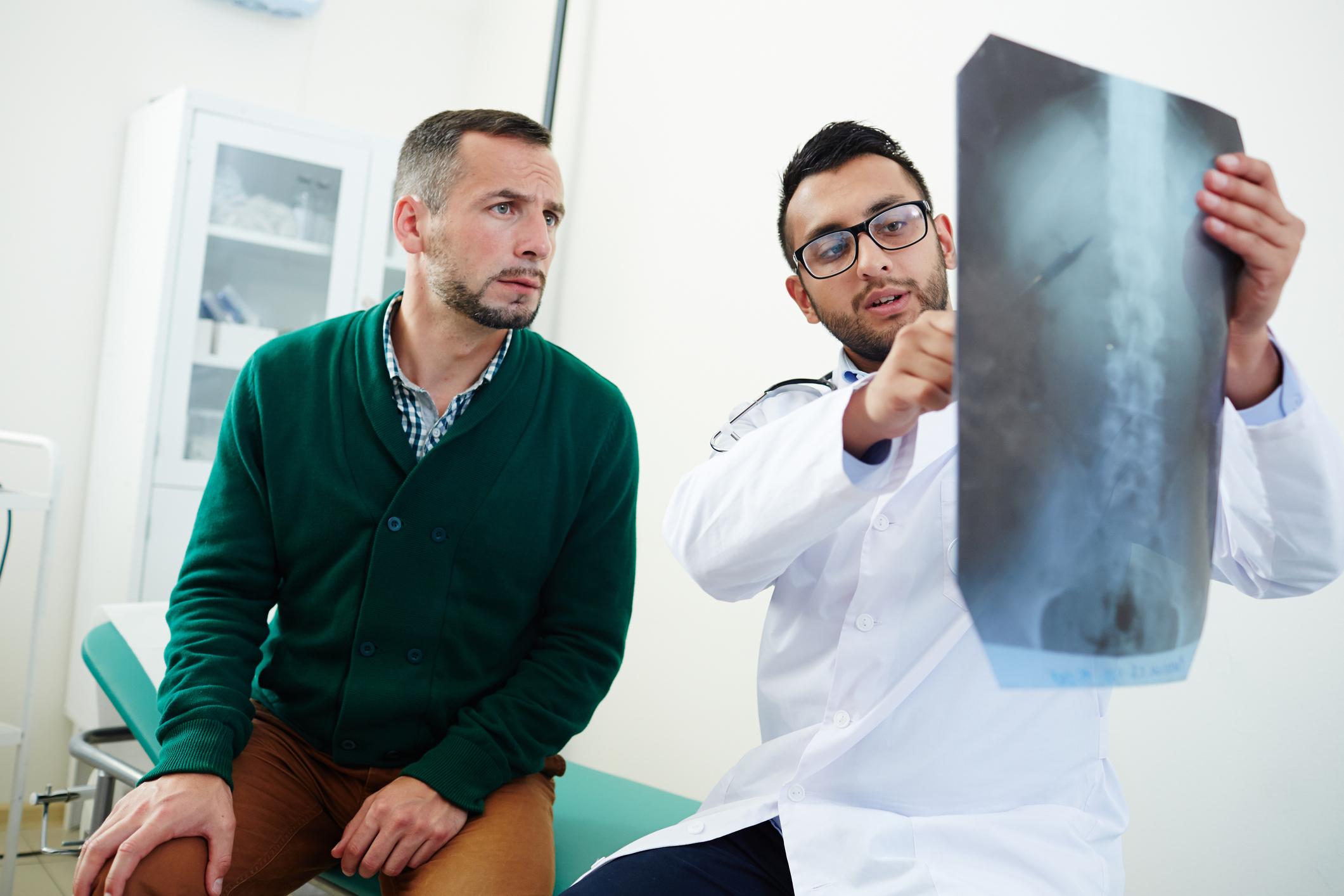 Doctor shows spinal xray to young man who looks concerned