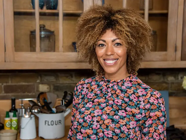 Dr Zoe Williams smiling to camera in her kitchen